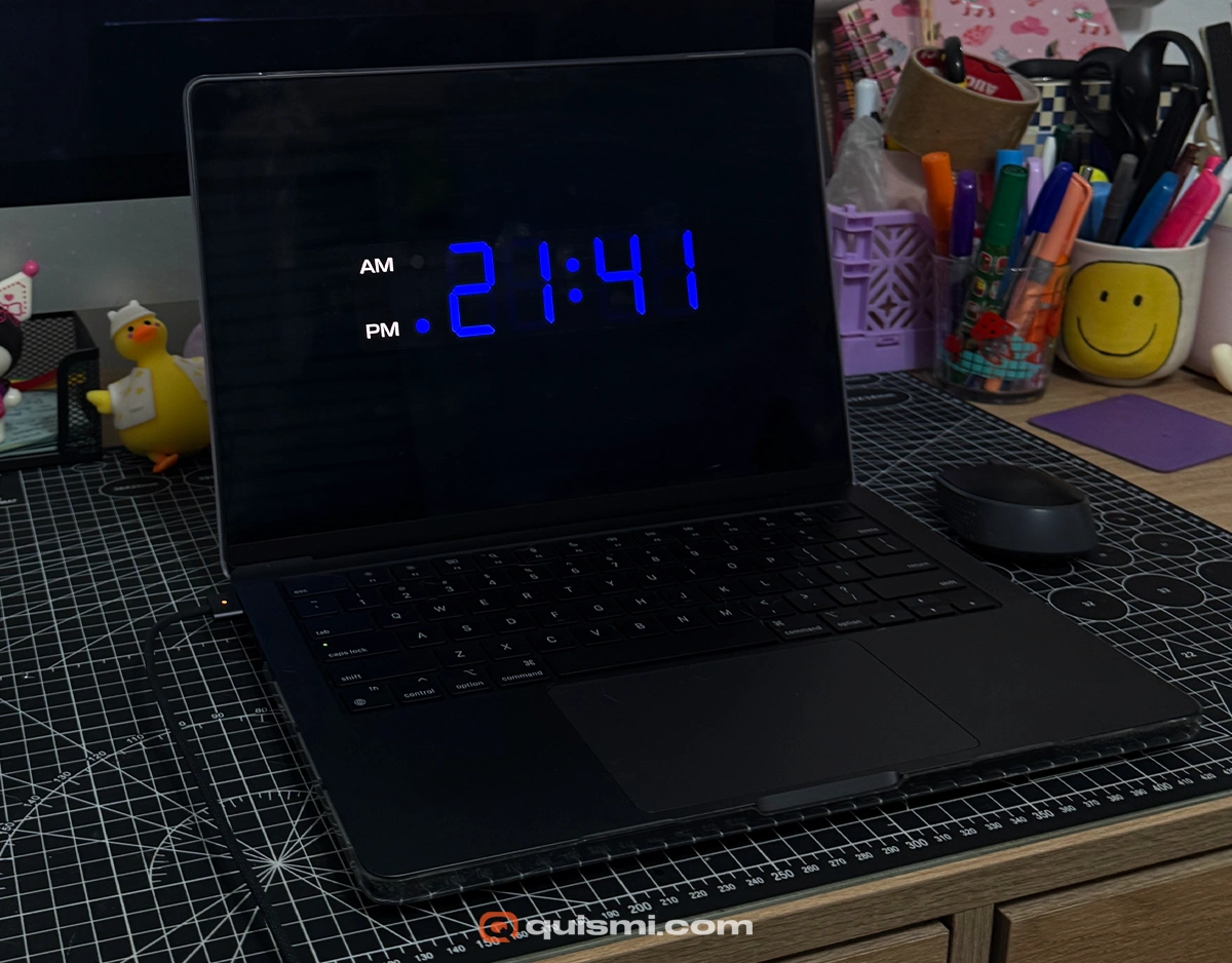 Close-up of a MacBook screen running the "Digital Electric" screensaver with bright blue numbers.
