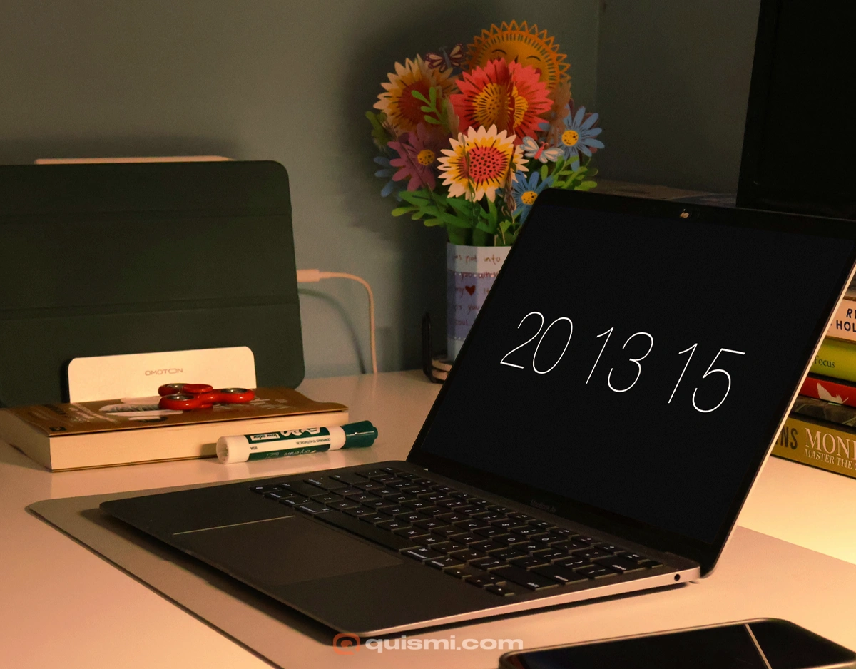 MacBook Pro with minimalist Padbury Clock screensaver showing clean white text on black background in office setting.